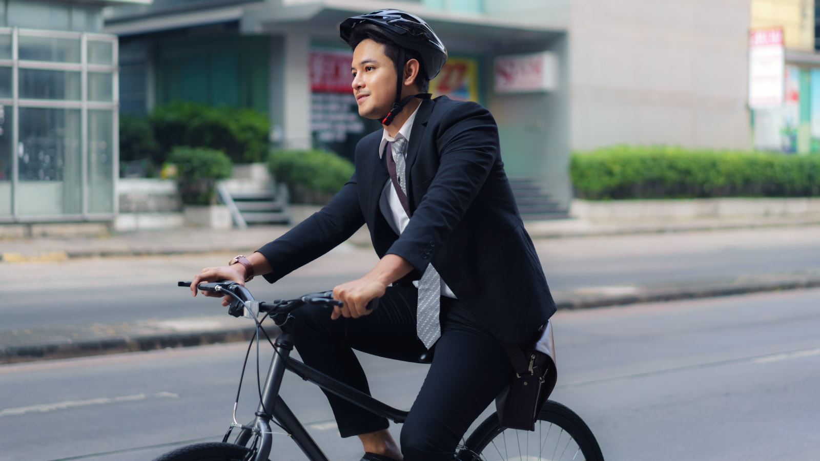 Pria muda mengenakan jas bersepeda ke kantor sebagai pilihan transportasi ramah lingkungan dan sehat
